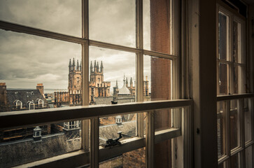 Roofs and old town towers at the city of Edinburgh seen through a window in a bad weather day. - Powered by Adobe