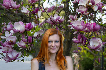 Portrait of beauty young redhead woman in magnolia tree, front view