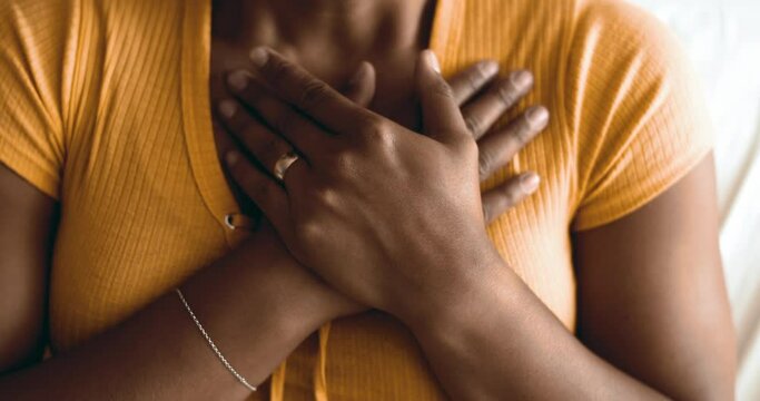 Spiritual Young African American woman putting hands on chest having HOPE and FAITH. Person gesturing heart-warming symbol of gratitude