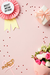 Vertical flat lay composition with rosette best mom ever, gift box, bouquet of flowers on pink background with confetti. Happy Mothers Day vertical banner design.