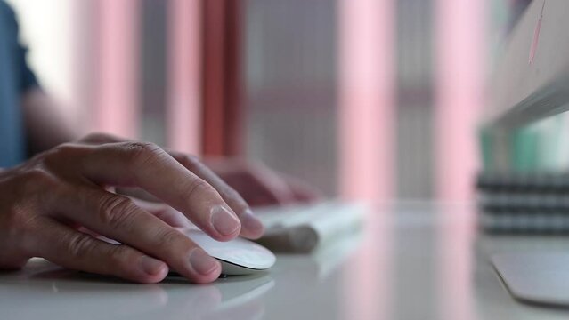 Hand using computer mouse working on table in modern office 