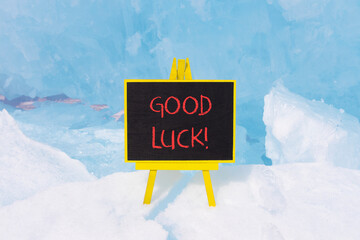 Good luck symbol. Concept words Good luck on beautiful yellow black blackboard. Beautiful blue ice background. Business, motivational good luck concept. Copy space.