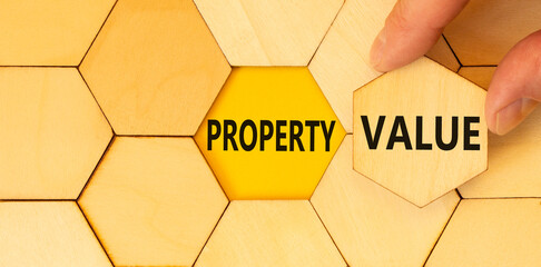 Property value symbol. Concept words Property value on beautiful wooden puzzle. Beautiful yellow table yellow background. Businessman hand. Business property value concept. Copy space.