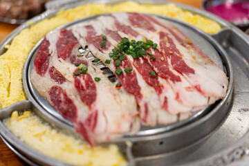 Korean barbecue restaurant, the waiter lays a barbecue net on the red environmentally friendly barbecue charcoal and uses food tongs to place strips of beef belly. A tutorial on cooking delicious 