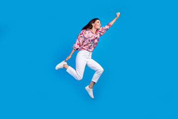 Fototapeta na wymiar Full length photo of funky cheerful lady dressed print shirt jumping high running empty space isolated blue color background