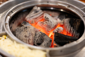 Korean barbecue restaurant, the waiter lays a barbecue net on the red environmentally friendly barbecue charcoal, and uses food tongs to place the beef bones and meat, teaching delicious and juicy 
