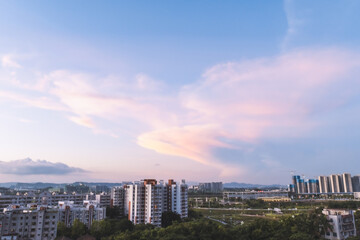 The central government building of Xiegang Town, Dongguan City, Guangdong Province, China. The sun shines through the clouds at sunset and dyes the blue sky and white clouds pink, which is beautiful 