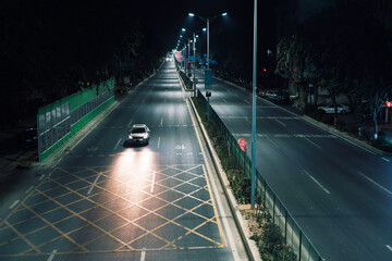 Night view of Xiegang Town, Dongguan City, China, on the wide road under the overpass, a car drives...
