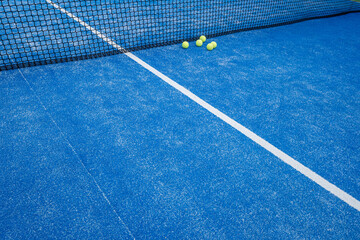 five balls next to the net of a paddle tennis court