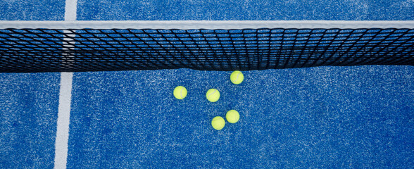 view from above of five balls next to the net of a paddle tennis court