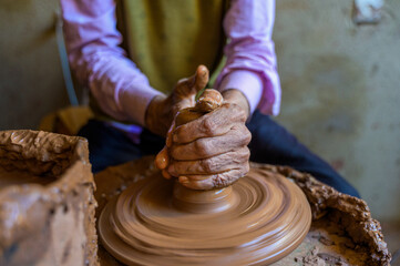 Artisan shaping clay on pottery wheel in workshop
