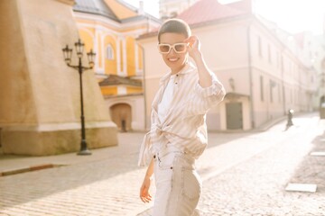 Stylish woman with short hair posing near on street of city.  Urban street fashion concept.