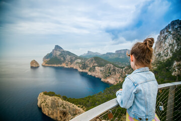 Back view of a little girl watching a beautiful view to the cape Formentor from Mirador de El Colomer in Mallorca