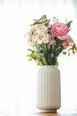 A colorful bouquet of flowers in various shapes and sizes graces a ribbed white vase
