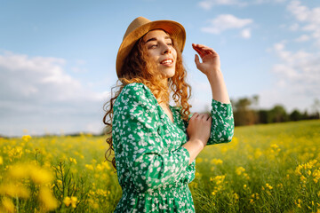 Young woman walks through a field of yellow flowers. Fashion, lifestyle, travel and vacations concept.