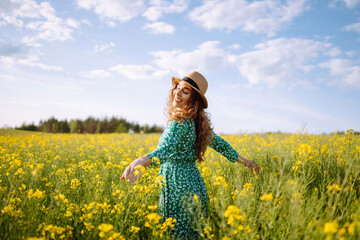 Young woman walks through a field of yellow flowers. Fashion, lifestyle, travel and vacations concept.