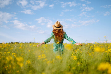 Young woman walks through a field of yellow flowers. Fashion, lifestyle, travel and vacations...
