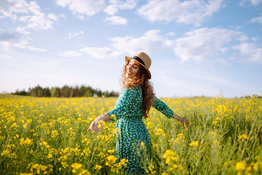 Young woman walks through a field of yellow flowers. Fashion, lifestyle, travel and vacations concept.