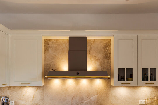 Modern kitchen hood and cabinets with warm lighting