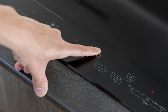 Anonymous person adjusts settings on a sleek induction stove