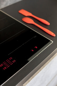 Modern induction stove with red silicone utensils