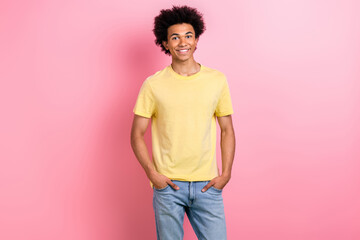 Photo of cheerful good mood guy dressed yellow t-shirt smiling hands arms pockets isolated pink...