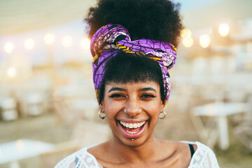 Bohemian african girl smiling on camera with beach bar on background - Summer lifestyle, travel and vacation concept - Focus on eyes.