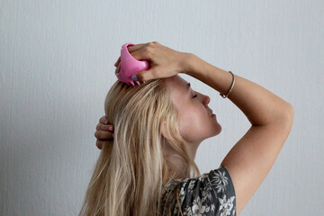 Woman using pink scalp massager for hair growth stimulating. Hair care pink silicone head massager.