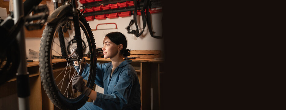 Bicycle female mechanic repairing bicycle doing his professional work in workshop or garage.