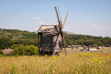 Fototapeta premium Wind Farm. Dutch windmill. Landscape with traditional Ukrainian windmills houses in countryside village. Windmill mill at rural outdoor. Wind mill. Windmill in a rural area. Traditional milling