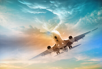 A commercial jet plane flies above dramatic clouds in the light of a beautiful sunset. Travel...