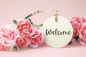 Welcome tag with carnation flowers on pink background