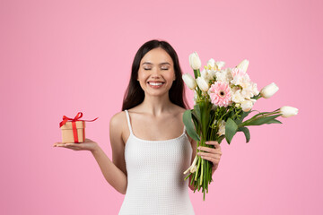 Lady holding bouquet and a gift on pink background