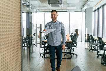 Handsome man with documents. Team of office workers are together indoors