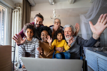 Happy multi-generation diverse family gathering around notebook and having fun during a video call - 781287144