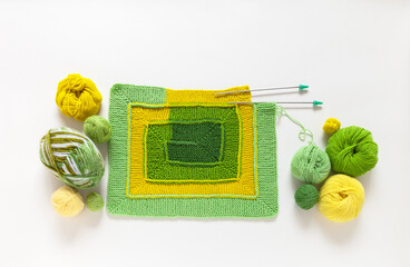 Handmade knitting square pattern using 10-stitch method from wool yarn in different shades of green color. DIY concept. Spring crafts and needlework. Flat lay, copy space, top view, close-up, mock up