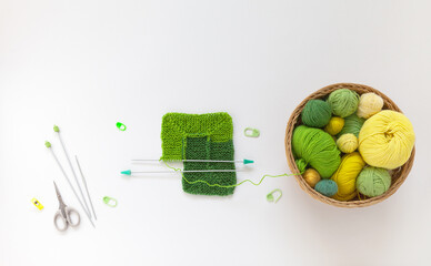 DIY concept. Hand knitting square pattern using 10-stitch method from wool yarn in different shades of green color. Spring crafts and needlework. Flat lay, copy space, top view, close-up, mock up