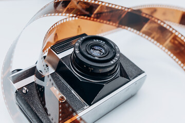 An artistic display of a vintage camera intertwined with a curling film reel, evoking nostalgia for classic photography and film.
