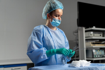 in the operating room the in green gloves lays out instruments on the surgical bedside table