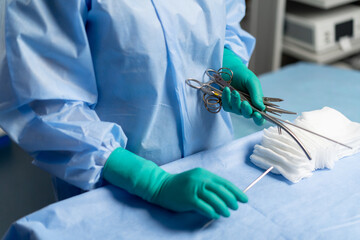 close up in the operating room the in green gloves lays out instruments on the surgical bedside...