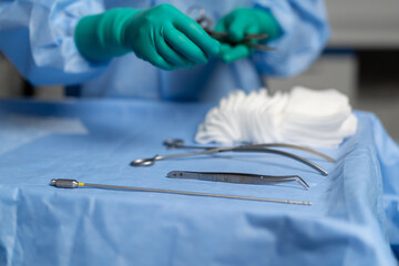 close up in the operating room the in green gloves lays out instruments on the surgical bedside...