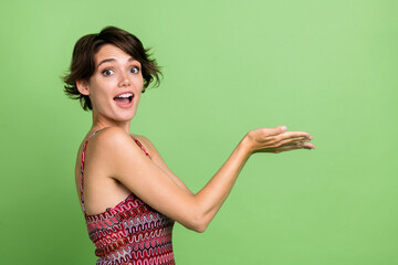 Photo of excited lovely nice girl wear trendy clothes introduce empty space novelty isolated on green color background