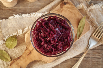 Purple fermented cabbage or sauerkraut in a glass bowl on a wooden table