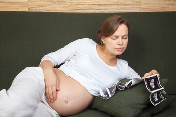 Expectant mother looking at sonograms on couch