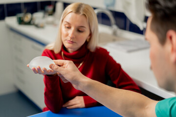 in a plastic surgery clinic a young girl is consulted on breast augmentation and examines an implant