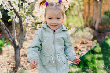 Portrait of smiling child girl in spring blooming garden. - 781298913