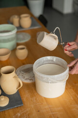 Fototapeta na wymiar Close-up of a potter's hands glazing a ceramic mug. Vertical photo. 