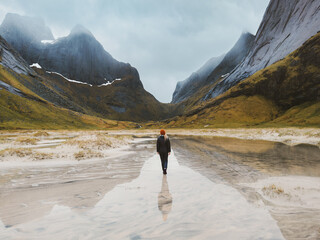 Traveler woman walking alone on flooded Horseid beach sandy dunes in Norway travel lifestyle summer vacations in Lofoten islands outdoor mountains water reflection, eco tourism - obrazy, fototapety, plakaty