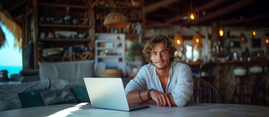 Young man with an opened laptop. He works as a freelancer near beach. Online teacher, student, investor or remote developer