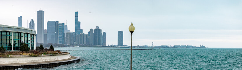 The Shedd Aquarium in Chicago stands against the backdrop of the city's shoreline along Lake Michigan, with a misty skyline.
